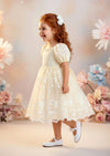 Knee‑length ivory baptism dress featuring embroidered lace and puff sleeves