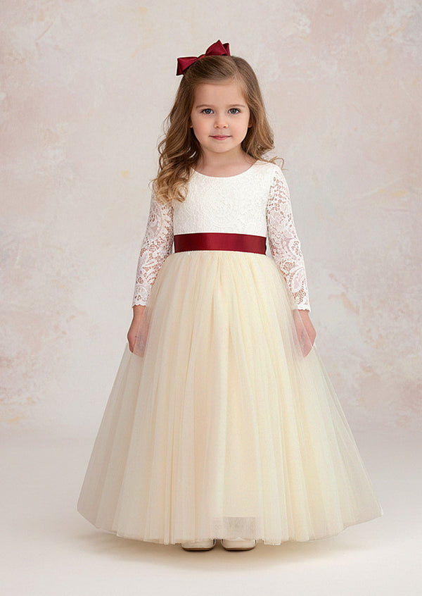 An elegant ivory flower girl dress featuring a lace bodice, feathered V‑back, and long tulle skirt. Includes a complimentary satin sash. Ideal for vintage and rustic weddings.