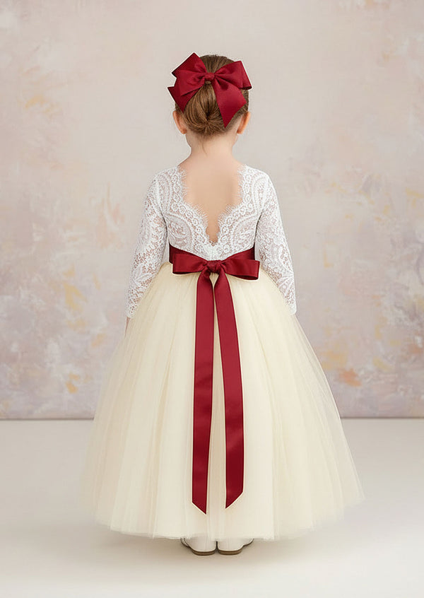 An elegant ivory flower girl dress featuring a lace bodice, feathered V‑back, and long tulle skirt. Includes a complimentary satin sash. Ideal for vintage and rustic weddings.