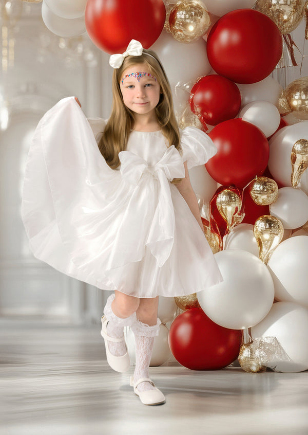 Little girl twirling in white Christmas dress with tulle skirt and sparkly accents
