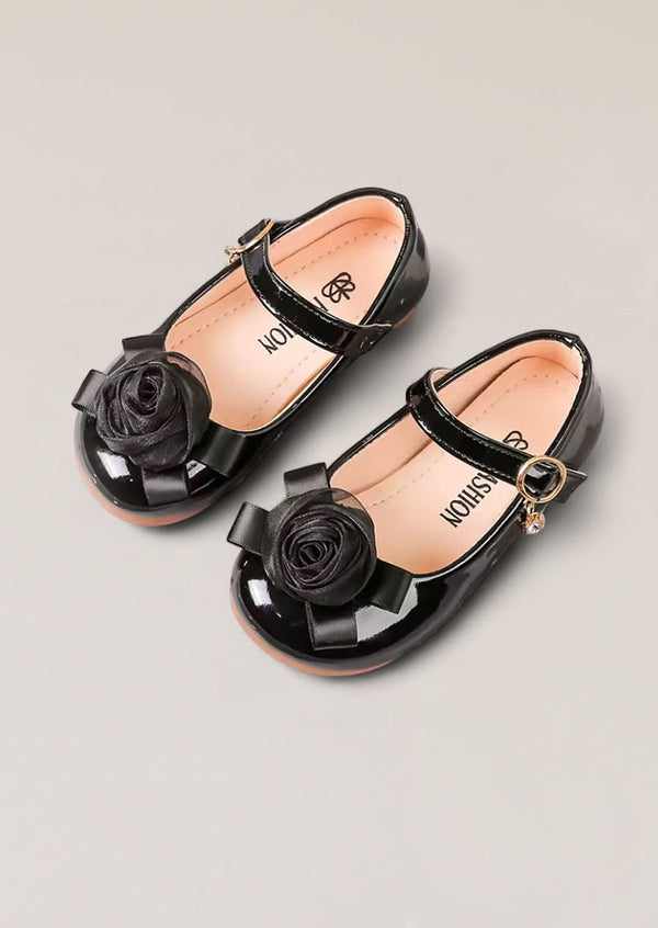 Toddler Girl Black patent leather shoes with rose details on a light gray background