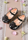Girls Black patent leather shoes with floral decorations on a decorative background