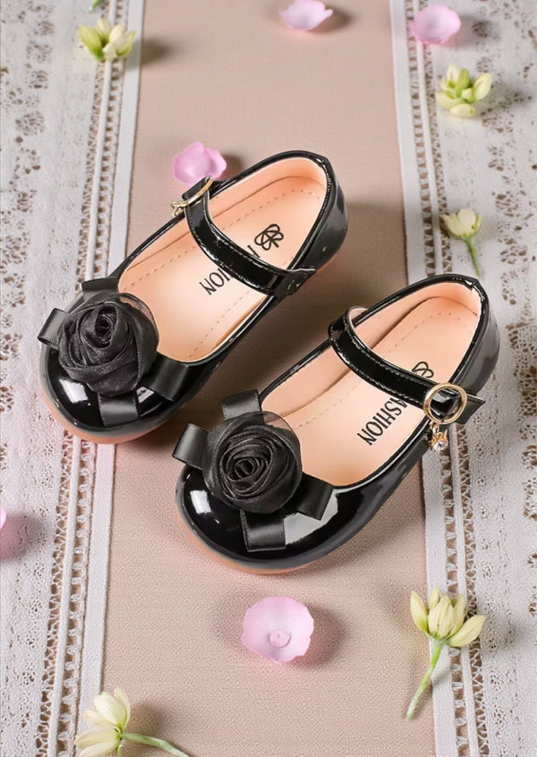 Girls Black patent leather shoes with floral decorations on a decorative background