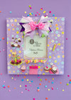 Handmade 11x11" lavender birthday photo frame with pastel floral paper, 3D cake & cupcake accents, ribbon bow, glass insert, and easel back. Holds 5x5" photo. One-of-a-kind and designer-signed.