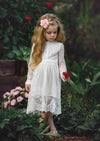 Little girl wearing Wisteria white lace dress with delicate buttons in garden setting